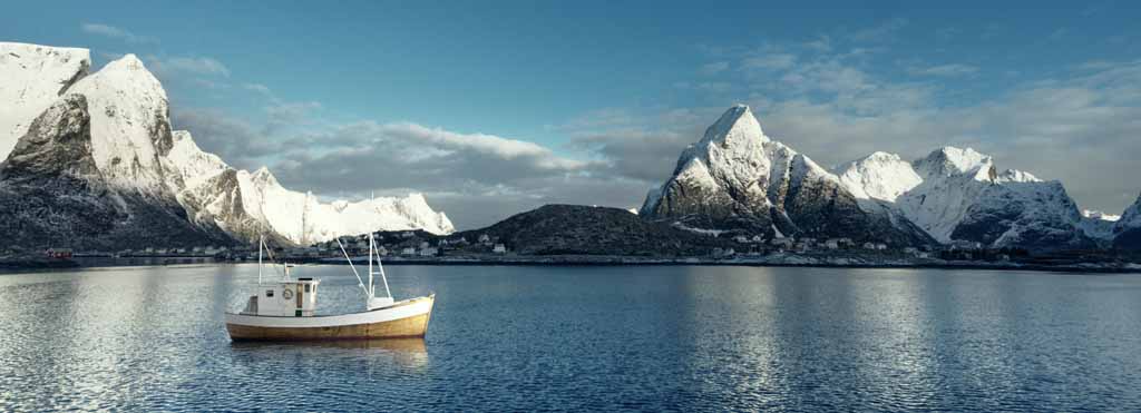 Boat on the water surrounded by snowy mountains
