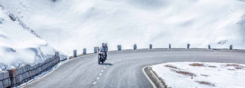 People riding on a motorcycle surrounded by snow