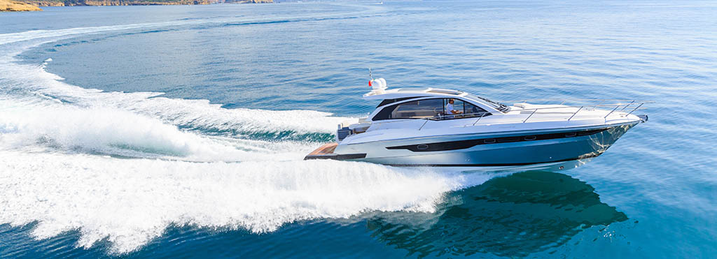 White luxury motor yacht speeding across calm blue sea - www.compassinsurancegroup.com